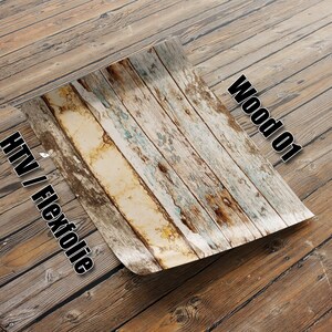 Puede incluir: Primer plano de una lámina de vinilo termoadhesivo (HTV) con patrón de veta de madera. La lámina está doblada por la mitad y se puede ver el texto "Wood 01" y "HTV / Flexfolie".