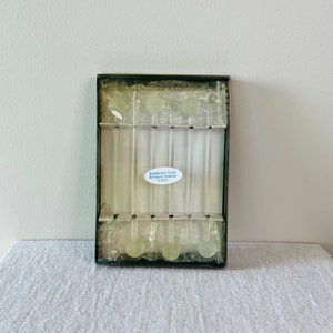 May include: A set of six clear glass drinking straws with green plastic tips, packaged in a clear plastic box with a green border. The box has a label that reads "Bloomingdale's Gift Collection, Made in Italy".