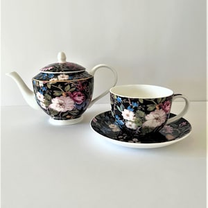 May include: A black and white floral tea set with a teapot and a cup and saucer. The teapot has a lid and a handle. The cup and saucer have a floral design.
