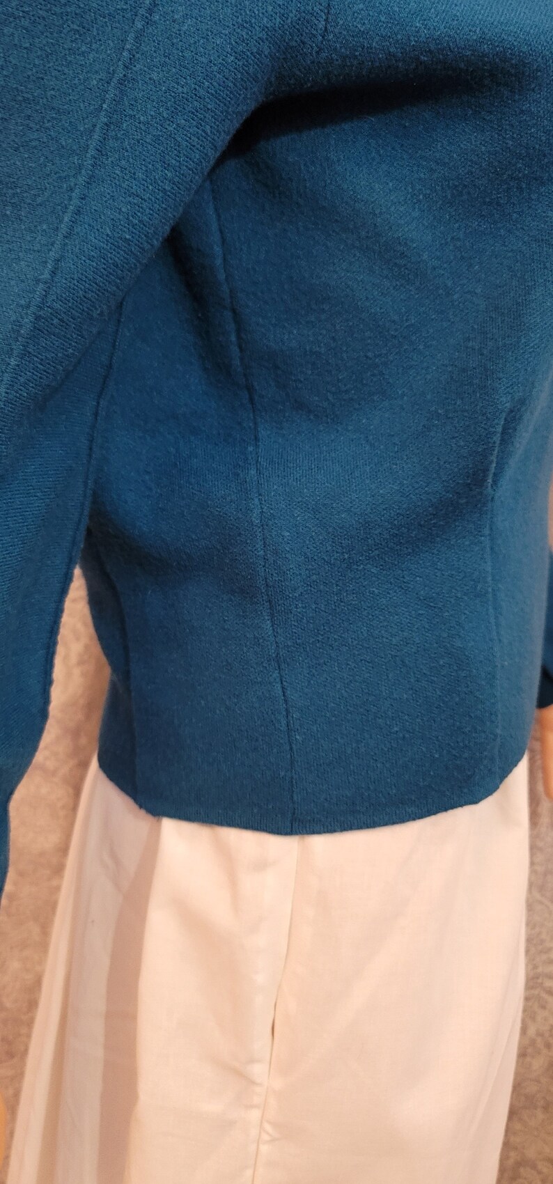 Pu&ograve; includere: Un blazer blu teal a maniche lunghe e chiusura con un solo bottone. Il blazer &egrave; realizzato in un tessuto morbido e testurizzato.