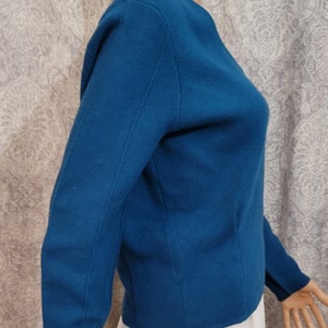 Pu&ograve; includere: Un maglione a maniche lunghe blu turchese con scollo rotondo. Il maglione &egrave; realizzato in un tessuto morbido e lavorato a maglia.
