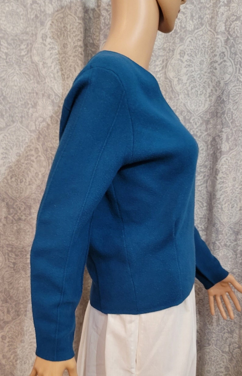 Pu&ograve; includere: Un maglione a maniche lunghe blu turchese con scollo rotondo. Il maglione &egrave; realizzato in un tessuto morbido e lavorato a maglia.