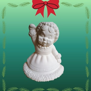 Może przedstawiać: Biała ceramiczna figurka kobiety w okularach, sukience i płaszczu z futrzanym obszyciem. Figurka macha. Czerwona kokarda i zielone gałązki sosny zdobią tło.