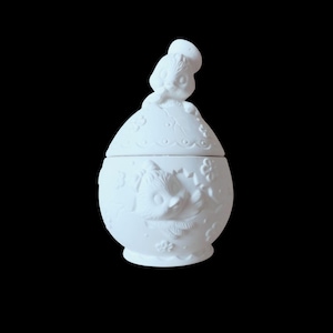 May include: White ceramic trinket box with a lid, featuring a sculpted design of a child figure on top and an owl on the side. The box has a round shape and is decorated with floral and leaf patterns.