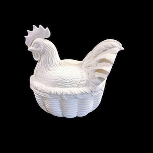 May include: A white ceramic hen figurine sitting in a woven basket. The hen has detailed feather and comb textures. The basket has a woven pattern. The background is black.