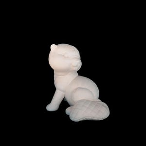 Puede incluir: Escultura blanca de un animal sentado, posiblemente un gato o un perro, con cuerpo redondeado y cola acolchada. La escultura tiene un acabado liso y está sobre un fondo negro.