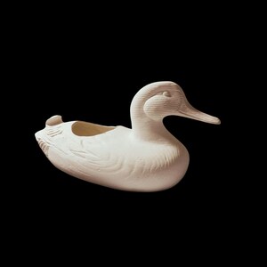 May include: White ceramic duck planter with a smooth, textured surface. The duck has a slightly open beak and a small hole in the back for drainage.