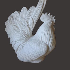 Puede incluir: Escultura de gallo de cerámica blanca con texturas detalladas de plumas y alas. El gallo está posado con las plumas de la cola extendidas y una cresta detallada. La escultura está sobre un fondo gris oscuro.