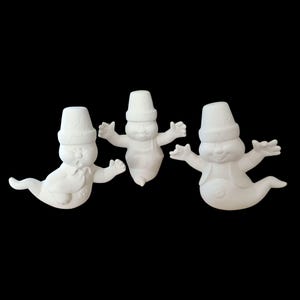 Puede incluir: Tres figuras de fantasmas blancas de cerámica con sombreros. Cada fantasma tiene una cara amigable y está en una pose de vuelo.
