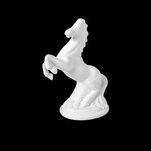 Puede incluir: Una estatua de caballo de cerámica blanca encabritada sobre sus patas traseras. El caballo tiene una melena y cola detalladas, y está sobre un fondo negro. La escultura es un objeto decorativo.
