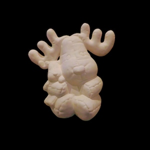 Puede incluir: Figura de alce de cerámica blanquecina. El alce tiene grandes cuernos y está sentado. La figura está sobre un fondo negro. Es un objeto decorativo.