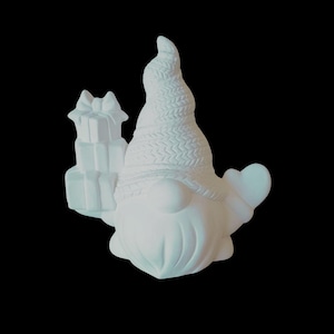 May include: A white ceramic gnome figurine holding a stack of gifts and a heart. The gnome has a long, pointed hat with a textured pattern and a long, white beard. The gifts are tied with a bow.