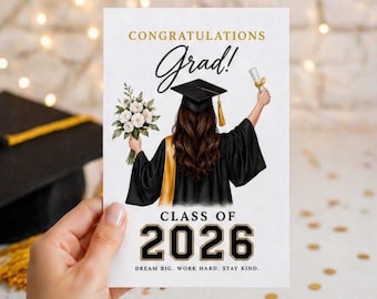 May include: A graduation card with the words "CONGRATULATIONS Grad! CLASS OF 2026" in gold and black. The illustration shows a graduate in a cap and gown holding flowers and a diploma. The card's message is "DREAM BIG. WORK HARD. STAY KIND."