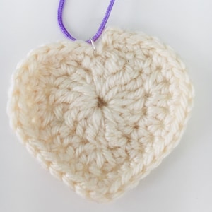 May include: A white crocheted heart-shaped ornament with a silver loop at the top.