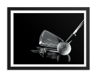 Op de afbeelding: Een zwart-wit afbeelding van een zilveren golfclub en een golfbal op een zwarte achtergrond. De club ligt op zijn zijde en de bal rust op de kop van de club.