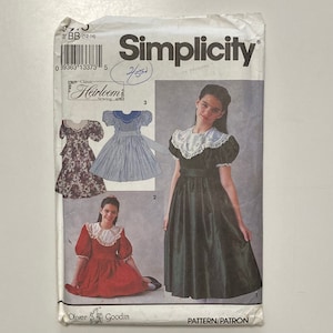 May include: Simplicity sewing pattern for a dress with a large collar. The pattern includes three different styles of dresses: a floral print dress, a striped dress, and a solid green dress. The pattern is for sizes 12-14.