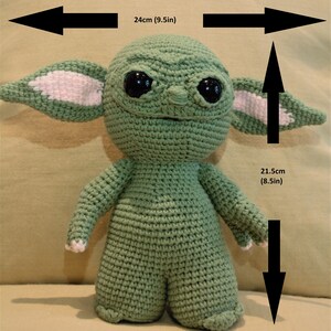 May include: Green crocheted plush toy of a character with large ears, big eyes, and a small mouth. The toy is 9.5 inches wide and 8.5 inches tall.