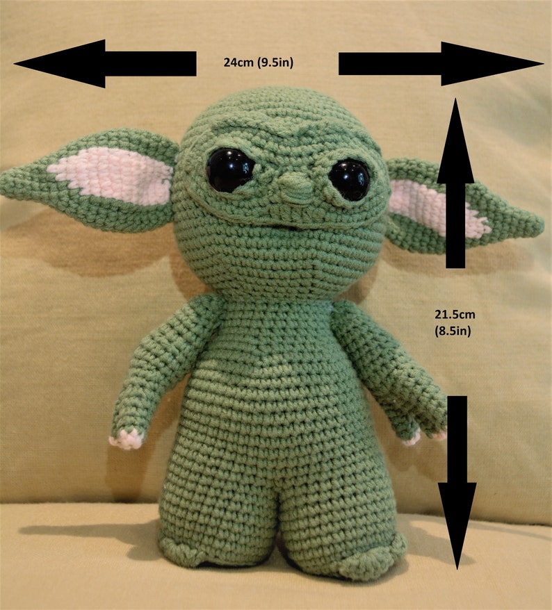 May include: Green crocheted plush toy of a character with large ears, big eyes, and a small mouth. The toy is 9.5 inches wide and 8.5 inches tall.