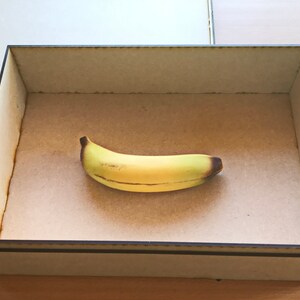 May include: A wooden box with a brown interior and a single yellow banana inside.
