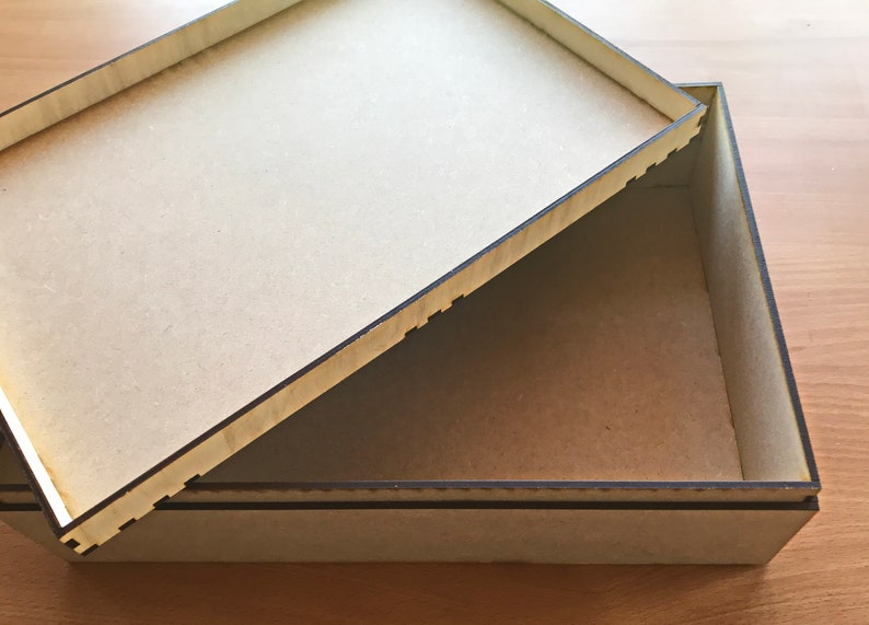 May include: A wooden box with a lid that is open. The box is made of light brown wood and has a dark brown border. The lid is also made of light brown wood and has a dark brown border.