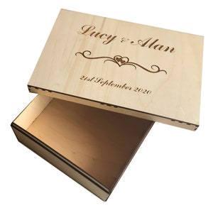 May include: A wooden box with a lid, engraved with the text "Lucy & Alan" and "21st September 2020". The lid is open and the box is empty.