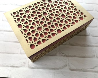 May include: A gold wooden box with a red geometric pattern cut out of the top. The box is made of wood and has a decorative design.