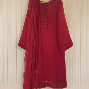 May include: A maroon-colored long-sleeved dress with a matching dupatta. The dress and dupatta are embroidered with sequins and beads.