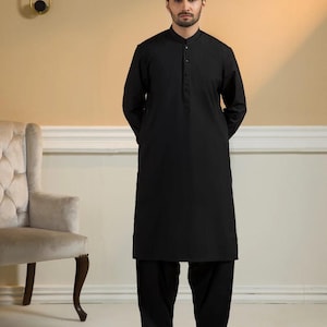 May include: A black kurta pajama set. The long-sleeved kurta has a mandarin collar and a button-down placket. The matching pajama pants are loose-fitting. The outfit is worn by a person standing in front of a neutral background.