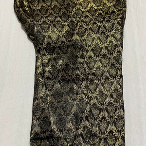 May include: Black fabric with a gold floral pattern. The fabric is folded in half.