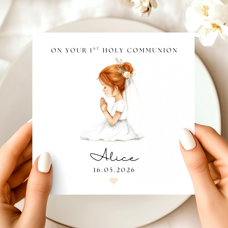 May include: A square card with the text "ON YOUR 1ST HOLY COMMUNION" and the name "Alice" with the date "16.05.2026". The card features an illustration of a girl in a white dress with red hair, praying. The card is held by two hands.