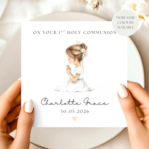 May include: A white square card featuring the text "ON YOUR 1ST HOLY COMMUNION" and a watercolour illustration of a girl in a white dress, hands clasped in prayer. The card is personalised with the name "Charlotte Grace" and the date "30.05.2026".