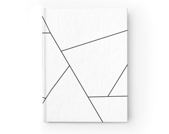 Puede incluir: Un cuaderno blanco con un diseño geométrico de líneas negras que forman triángulos y rectángulos.