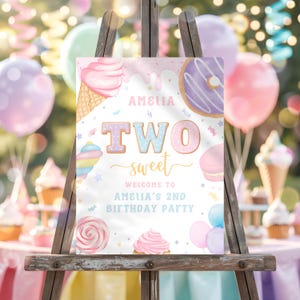 May include: A wooden easel displays a colorful sign for a second birthday party. The sign features illustrations of sweets like ice cream, donuts, and cupcakes. Text on the sign reads "Amelia is Two Sweet" and welcomes guests to the party.