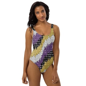 May include: One-piece swimsuit with a colorful binary code pattern. The swimsuit features a scoop neckline and a high-cut leg. The design incorporates vertical stripes in black, white, yellow, and purple, with binary code details.