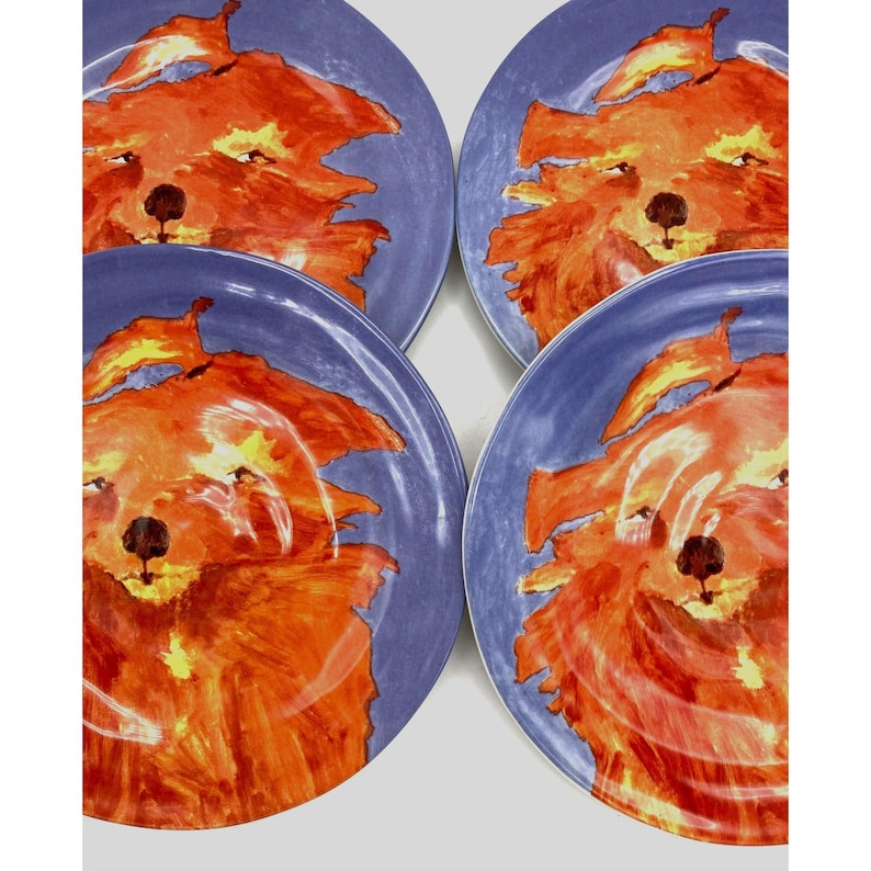 Pode incluir: Conjunto de quatro pratos de cer&acirc;mica. Cada prato apresenta um rosto de raposa laranja vibrante sobre um fundo azul. As raposas s&atilde;o pintadas com pinceladas. Uma adi&ccedil;&atilde;o &uacute;nica a qualquer cozinha. Di&acirc;metro aproximado de 20 cm.