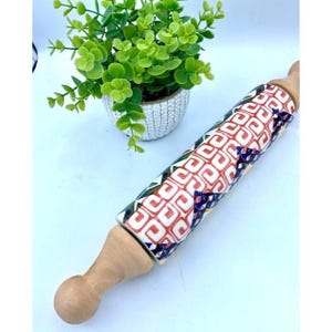 May include: A wooden rolling pin with a colorful geometric pattern. The pattern features red, blue, green, and yellow squares and triangles on a white background.