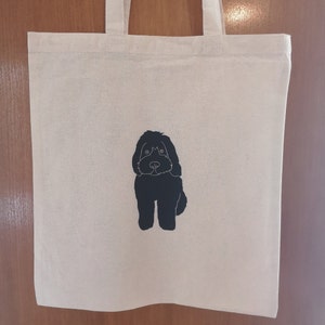 May include: A white canvas tote bag with a black silhouette of a dog printed on the front.