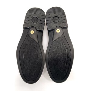 May include: A pair of black leather shoes with a textured sole. The soles are marked with the size 42.