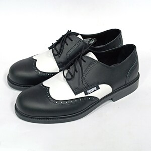 May include: Black and white leather brogue shoes with a white toe cap and black laces. The shoes have a black rubber sole and the word "BOOGIE" is printed on the side.