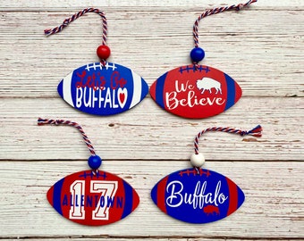 May include: Four blue and red football-shaped ornaments with white string and beads. The ornaments have the following text: "Let's Go Buffalo", "We Believe", "Buffalo", and "17 Allentown".