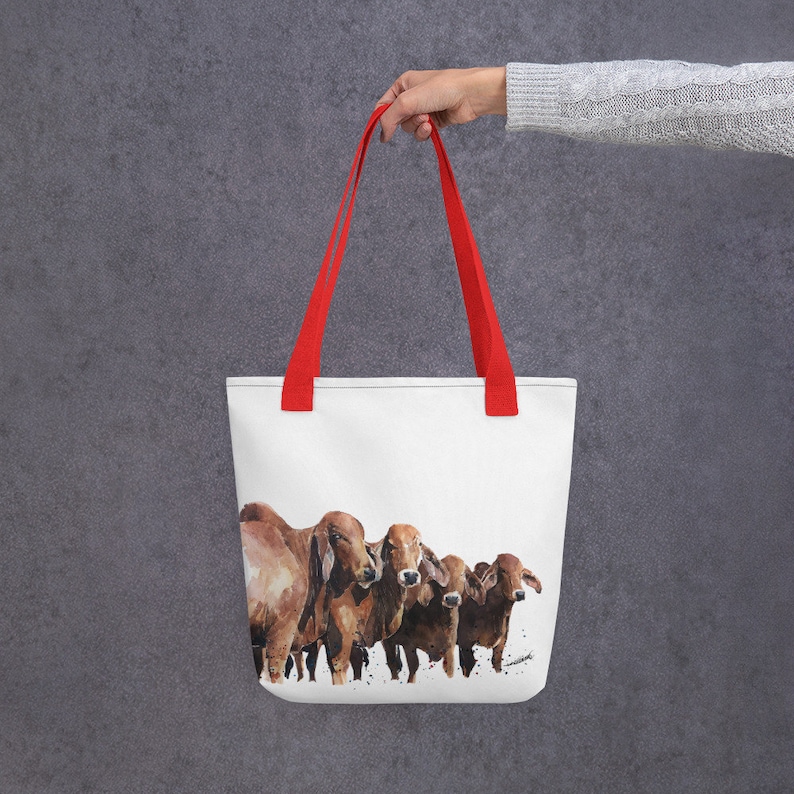 Op de afbeelding: Een witte tote bag met rode handvatten heeft een aquarel schilderij van vijf bruine koeien. De koeien staan in een rij en kijken naar de kijker.