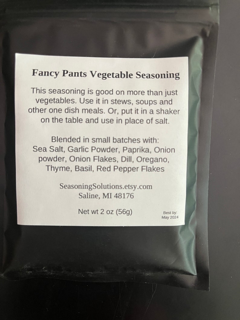 May include: A black and white label with the text "Fancy Pants Vegetable Seasoning" and a list of ingredients including sea salt, garlic powder, paprika, onion powder, onion flakes, dill, oregano, thyme, basil, and red pepper flakes. The label also includes the text "SeasoningSolutions.etsy.com", "Saline, MI 48176", "Net wt 2 oz (56g)", and "Best by: May 2024".