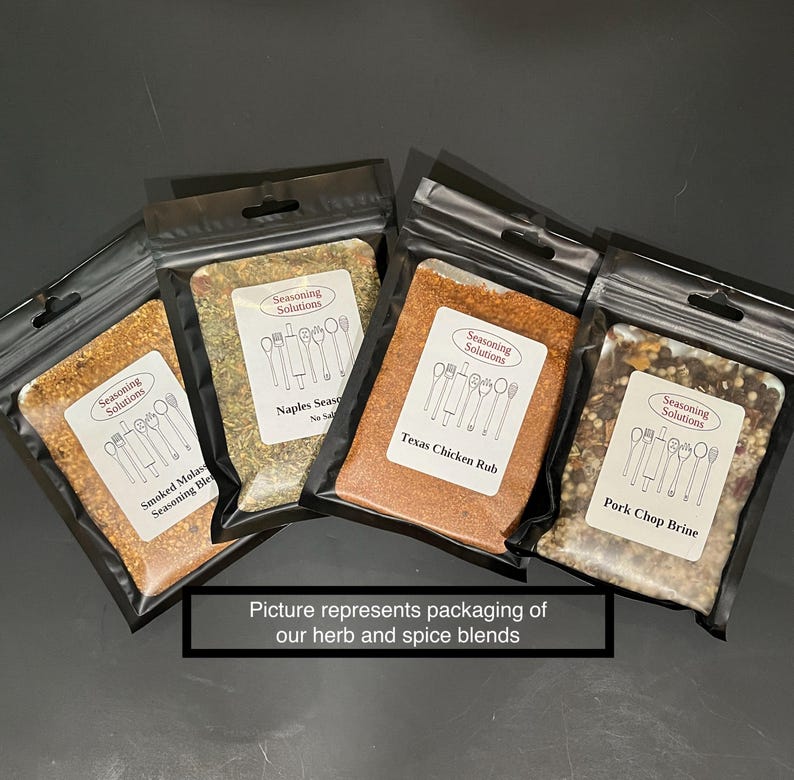 Peut inclure: Quatre petits sachets refermables noirs remplis de diff&eacute;rents m&eacute;langes d'&eacute;pices. Les sachets sont &eacute;tiquet&eacute;s avec le texte "Seasoning Solutions" et les noms des m&eacute;langes : "Smoked Molasses Seasoning Blend", "Naples Seasoning", "Texas Chicken Rub" et "Pork Chop Brine".