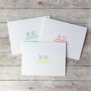 May include: Three white cards with the text "Oh, Hi!" written in black. Each card has a different colored line under the text: blue, pink, and yellow.