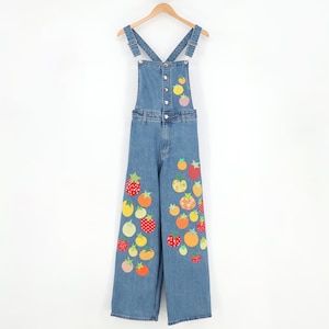 May include: Blue denim overalls featuring a straight-leg silhouette, adjustable shoulder straps, and a front button closure. The garment is decorated with a scattered pattern of colorful, patterned fabric fruit appliques in shades of red, orange, and yellow.