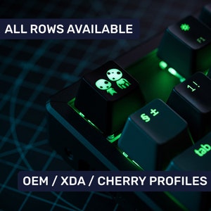 May include: A black mechanical keyboard with green backlighting. The keyboard has a keycap with a white graphic of two cartoon characters. The text "ALL ROWS AVAILABLE" and "OEM / XDA / CHERRY PROFILES" is visible on the image.