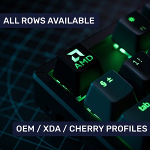 Peut inclure: Un clavier mécanique noir avec un rétroéclairage vert. Le clavier a un capuchon de touche avec le logo AMD. Le texte "ALL ROWS AVAILABLE" et "OEM/XDA/CHERRY PROFILES" est visible sur l'image.
