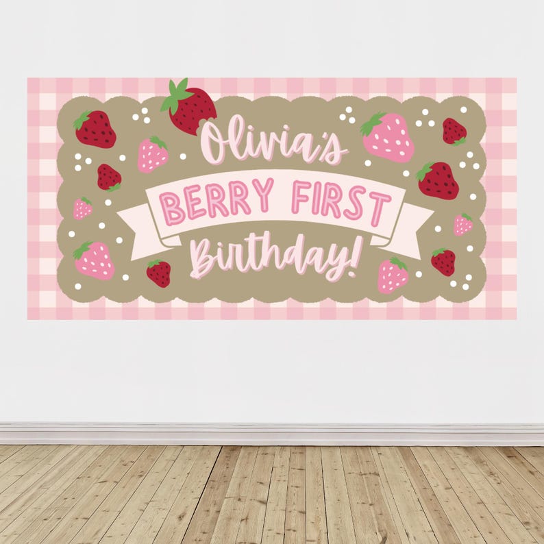 May include: A rectangular banner with a pink and white gingham pattern background. The banner features a brown scalloped border and the text "Olivia's BERRY FIRST Birthday!" in pink lettering. Red and pink strawberry illustrations are scattered across the banner.