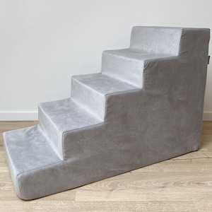 May include: Gray pet steps with five steps, made of soft fabric. The steps are angled and have a light gray color.