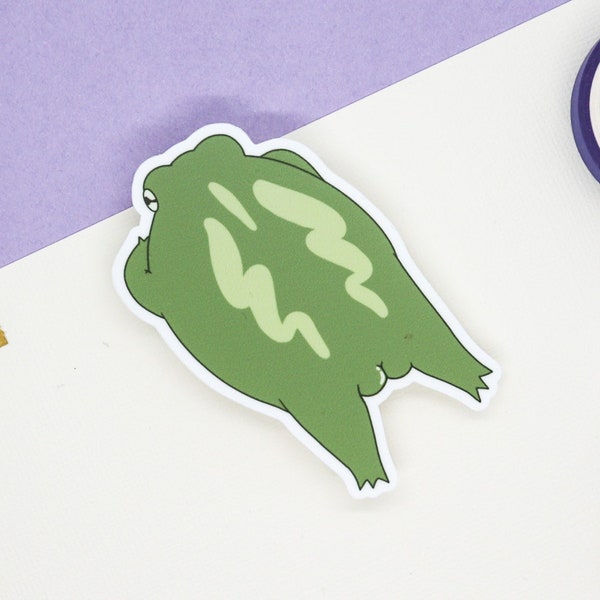 May include: A green frog sticker with a white outline. The frog is lying on its back with its legs in the air.